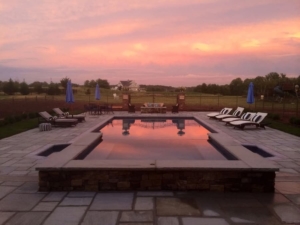 Pool-and-Patio-in-Backyard Outdoor Pool Surrounded By Chaise Lounges And Umbrellas At Sunset